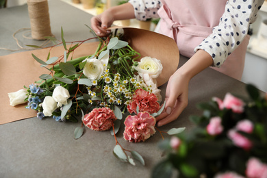 Photo of Florist making bouquet with fresh flowers at table, closeup