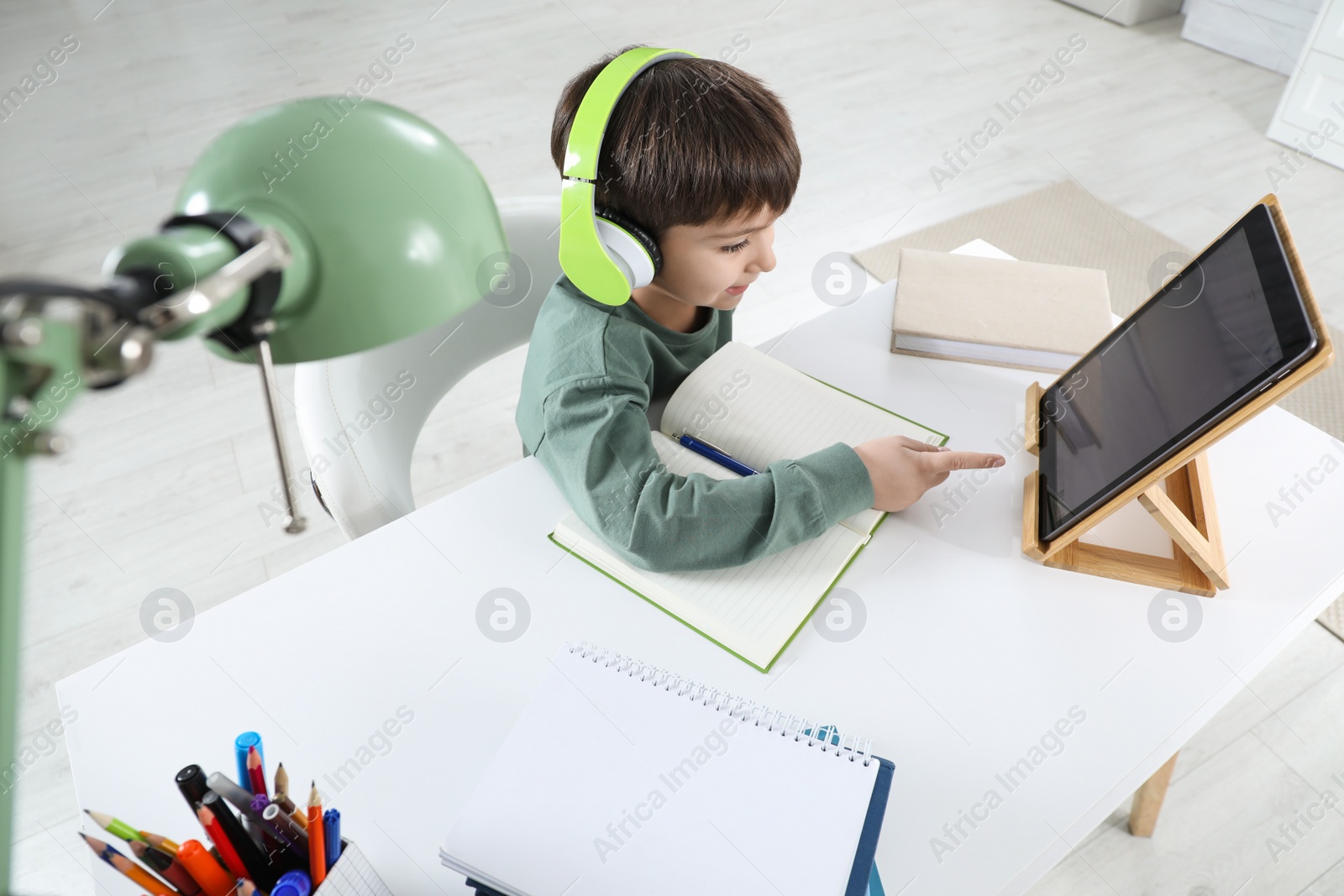 Photo of Cute little boy with modern tablet studying online at home. E-learning