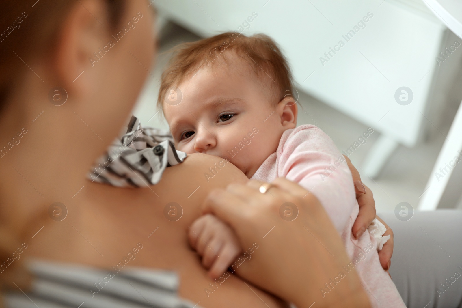 Photo of Young woman breastfeeding her baby at home, closeup