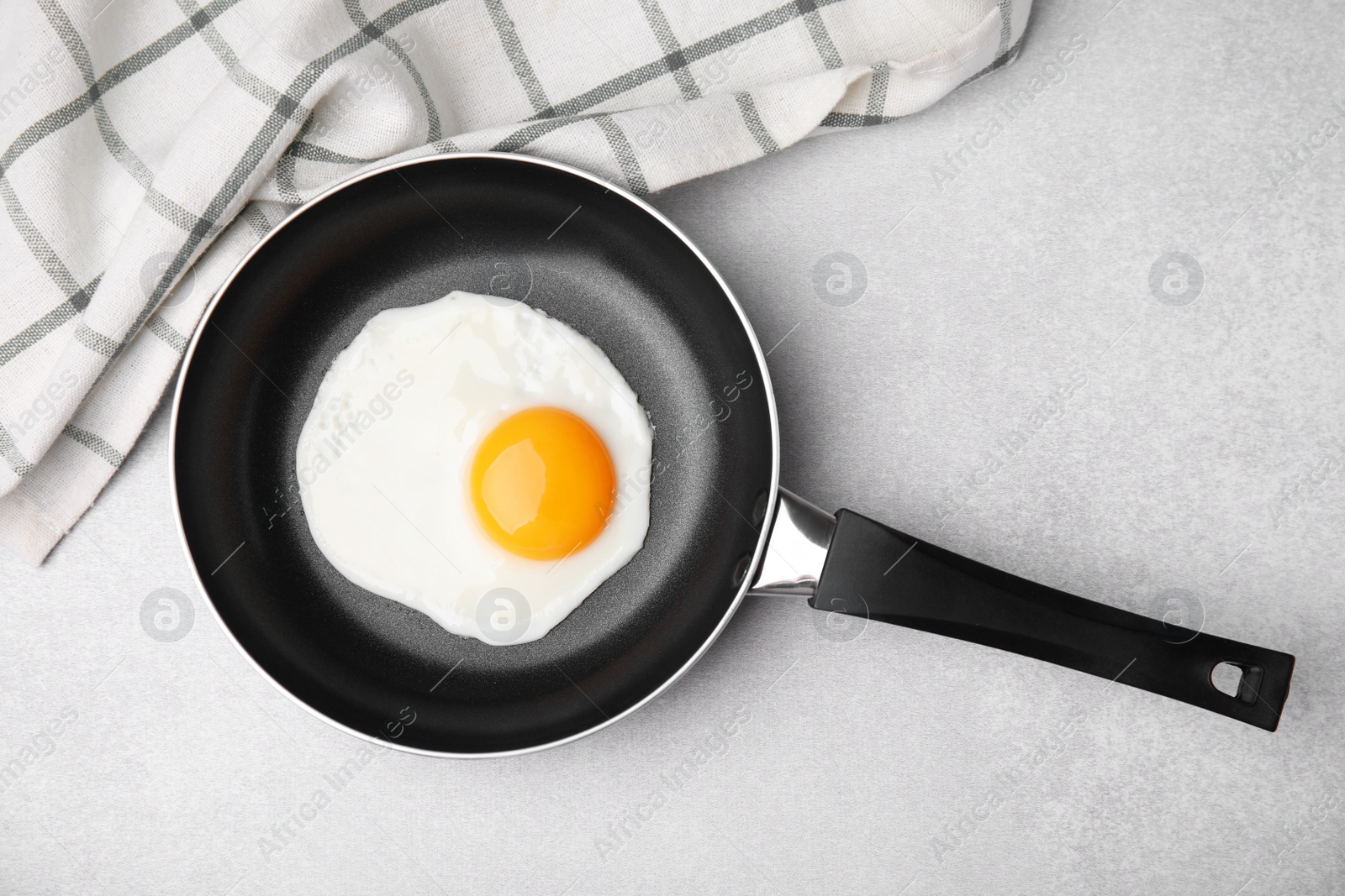 Photo of Tasty fried egg in pan on light grey table, flat lay