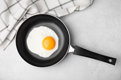 Tasty fried egg in pan on light grey table, flat lay