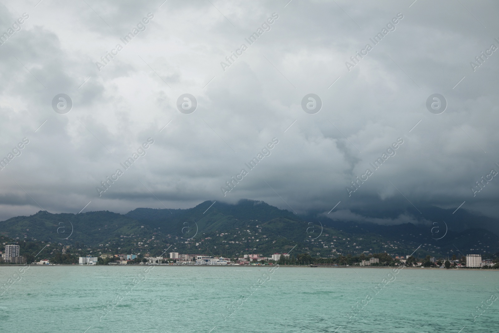 Photo of Picturesque view of sea with coastline and mountains under cloudy sky