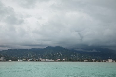 Photo of Picturesque view of sea with coastline and mountains under cloudy sky