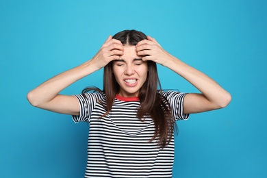 Photo of Young woman scratching head on color background. Annoying itch