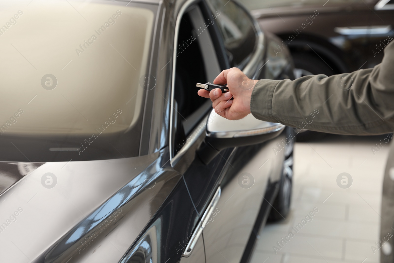 Photo of Young man checking alarm system with car key indoors, closeup