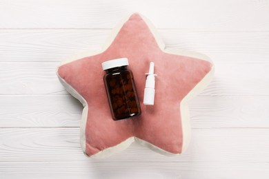 Pillow, pills and nasal spray on white wooden background, top view