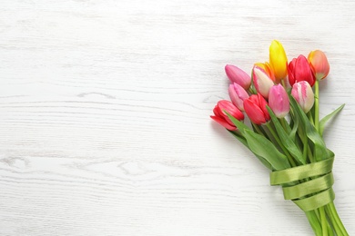 Photo of Beautiful bouquet of spring tulip flowers on wooden background, top view. Space for text