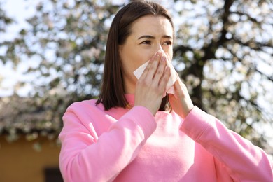 Woman with napkin suffering from seasonal allergy on spring day