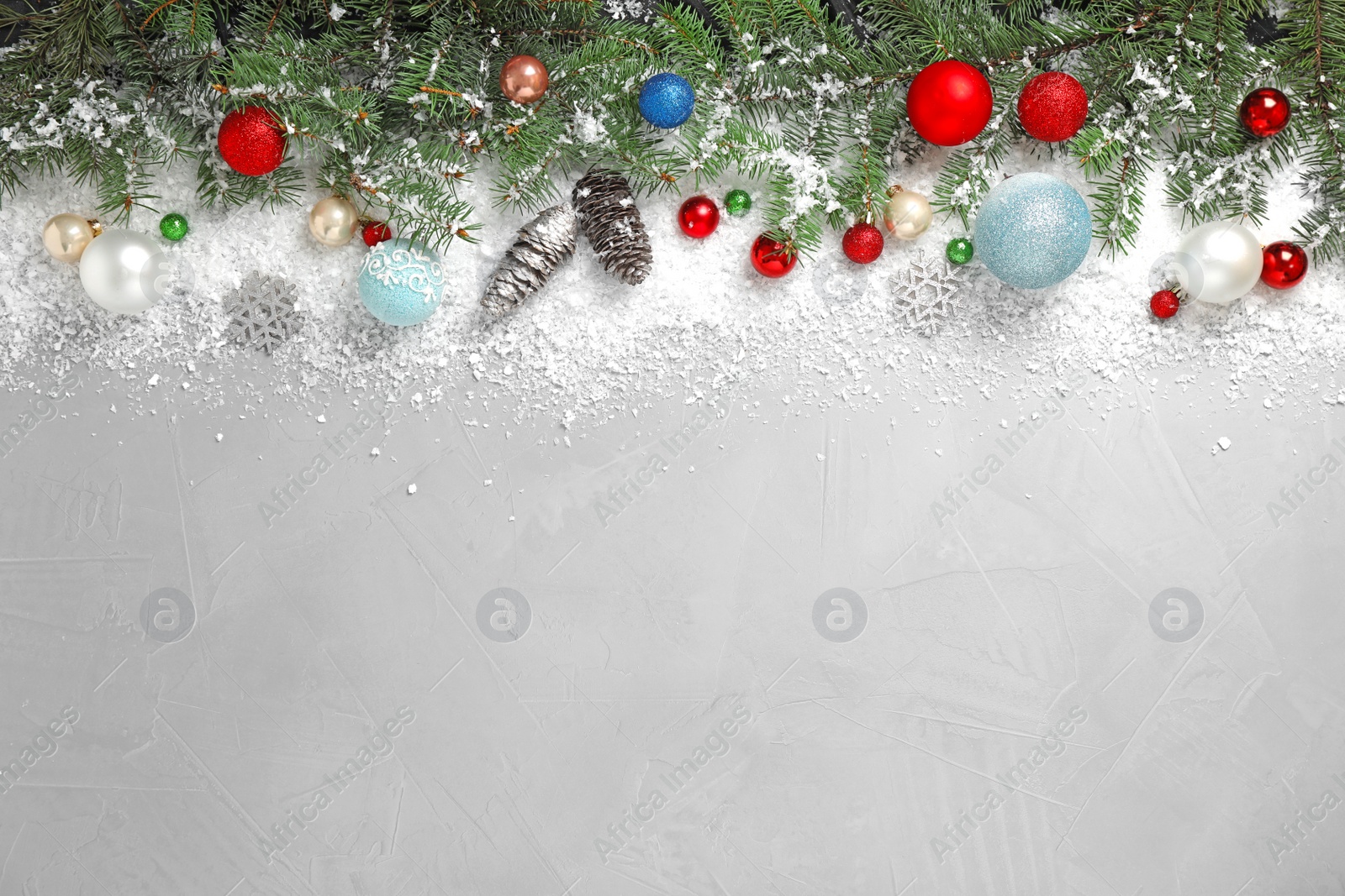 Photo of Christmas decoration with white snow on light grey stone background, flat lay. Space for text