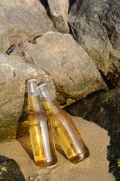 Photo of Bottles of cold beer near rock on sandy beach