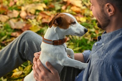 Photo of Man with adorable Jack Russell Terrier in autumn park, closeup. Dog walking