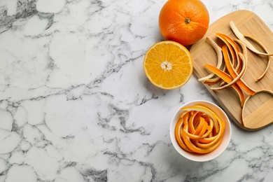 Orange fruits with peels on white marble table, flat lay. Space for text