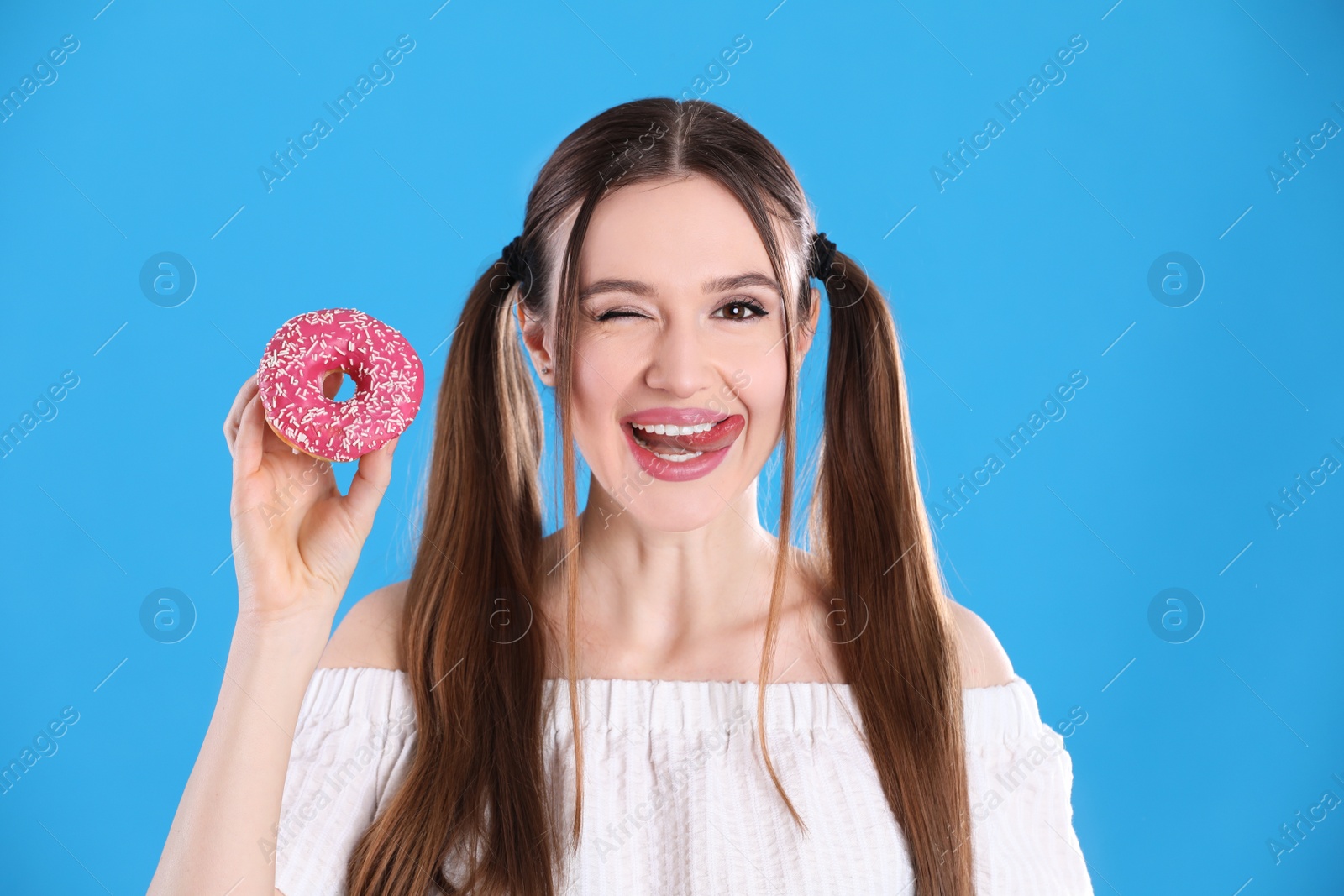 Photo of Beautiful young woman with donut on light blue background