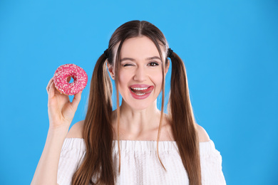 Photo of Beautiful young woman with donut on light blue background