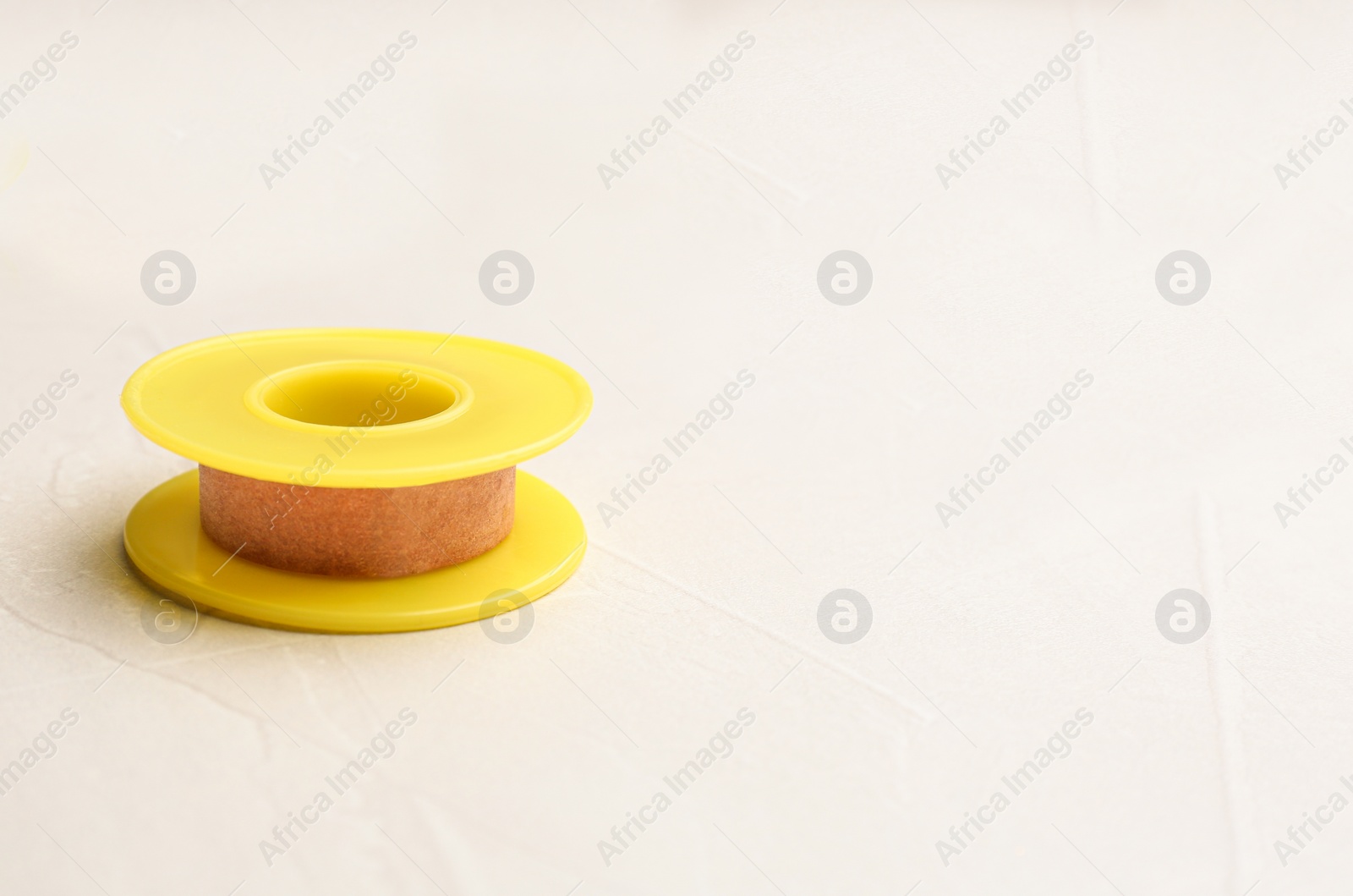 Photo of Sticking plaster roll on light stone background. Space for text