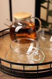Photo of Tray with clean glass cups and teapot on wooden table, closeup
