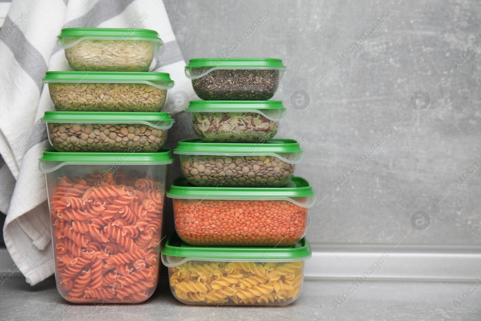 Photo of Plastic containers filled with food products on grey table. Space for text