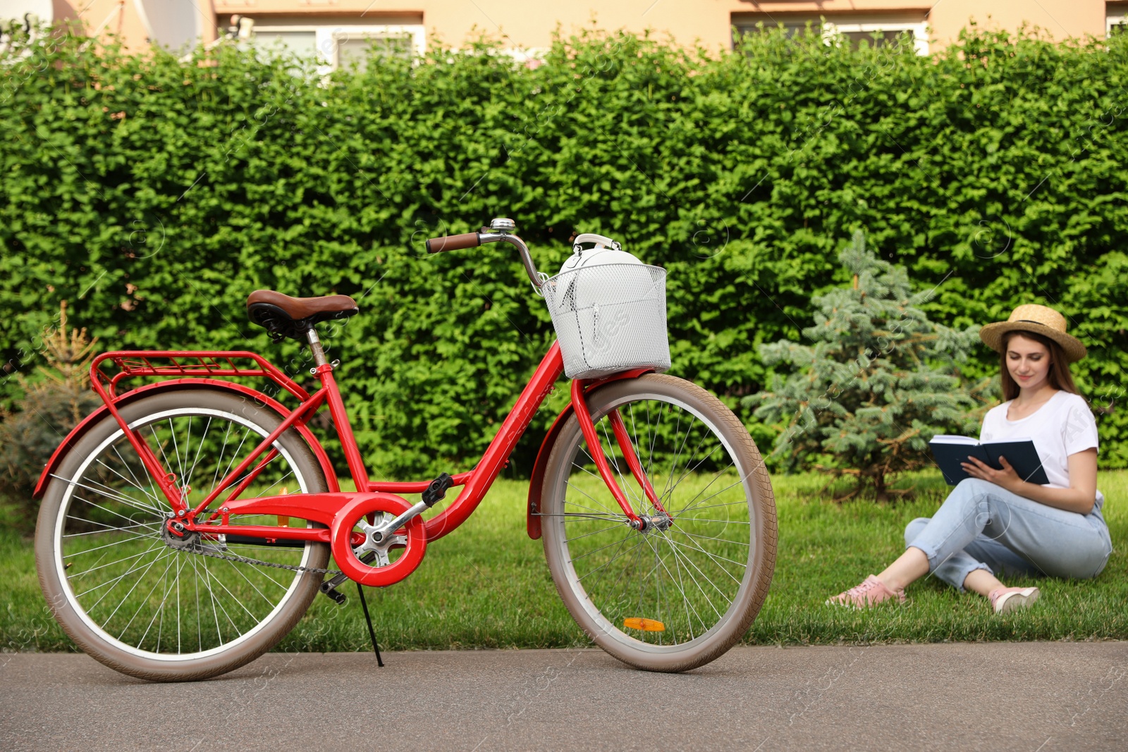 Photo of Young woman sitting near modern bicycle on grass outside