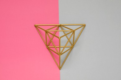 Photo of Golden decorative pyramid on color background, top view
