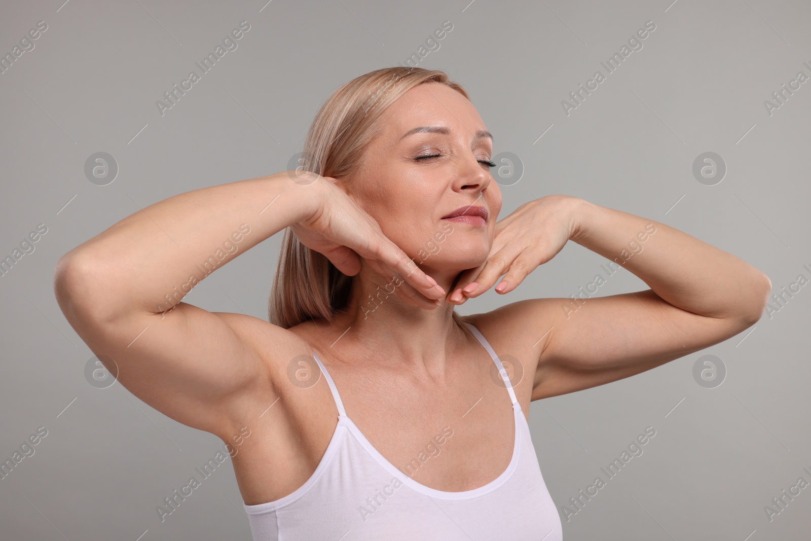 Photo of Beautiful woman touching her neck on grey background