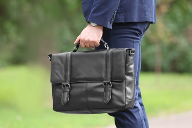 Businessman with black briefcase in hand outdoors, closeup