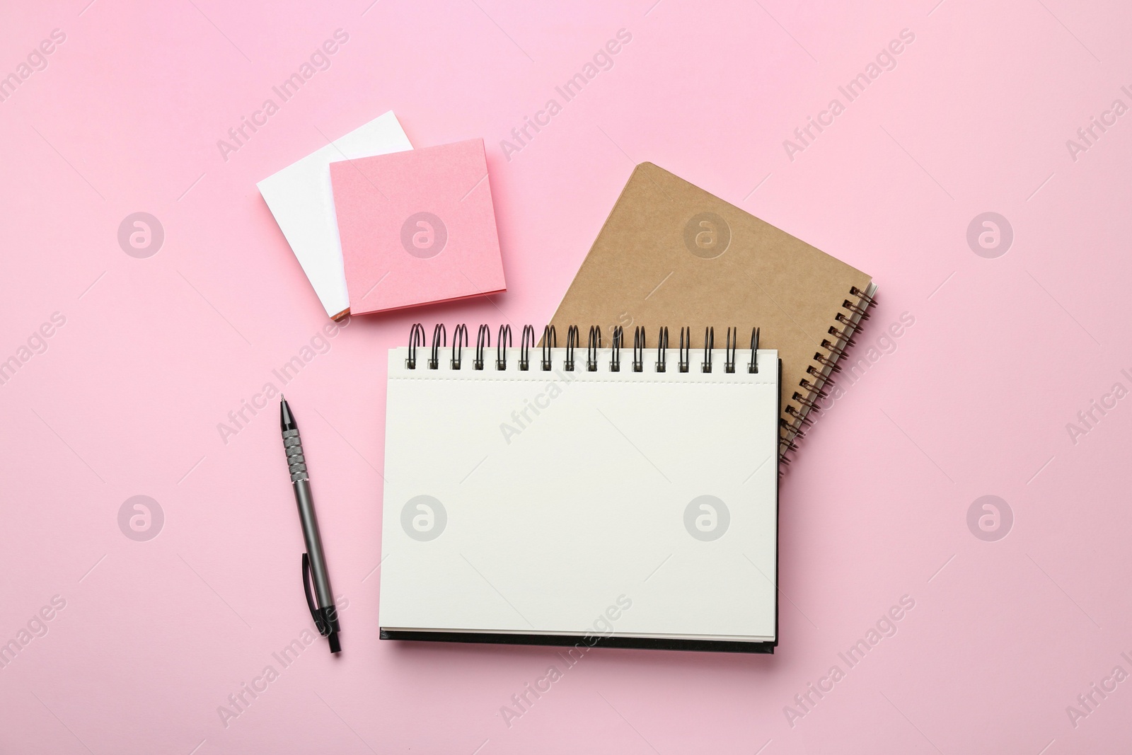 Photo of Notebooks, pen and sticky notes on pink background, flat lay
