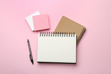 Notebooks, pen and sticky notes on pink background, flat lay