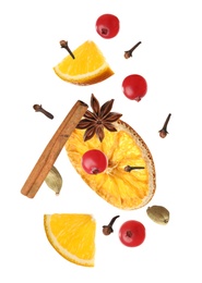 Cut orange, cranberries and different spices falling on white background. Mulled wine ingredients
