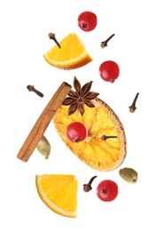 Image of Cut orange, cranberries and different spices falling on white background. Mulled wine ingredients