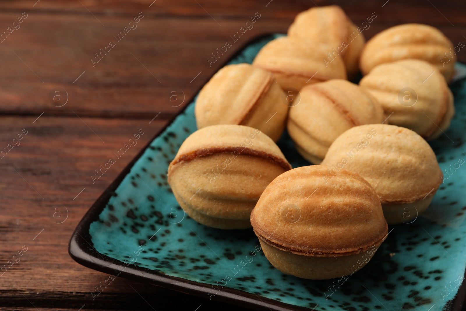 Photo of Delicious nut shaped cookies with boiled condensed milk on plate, closeup