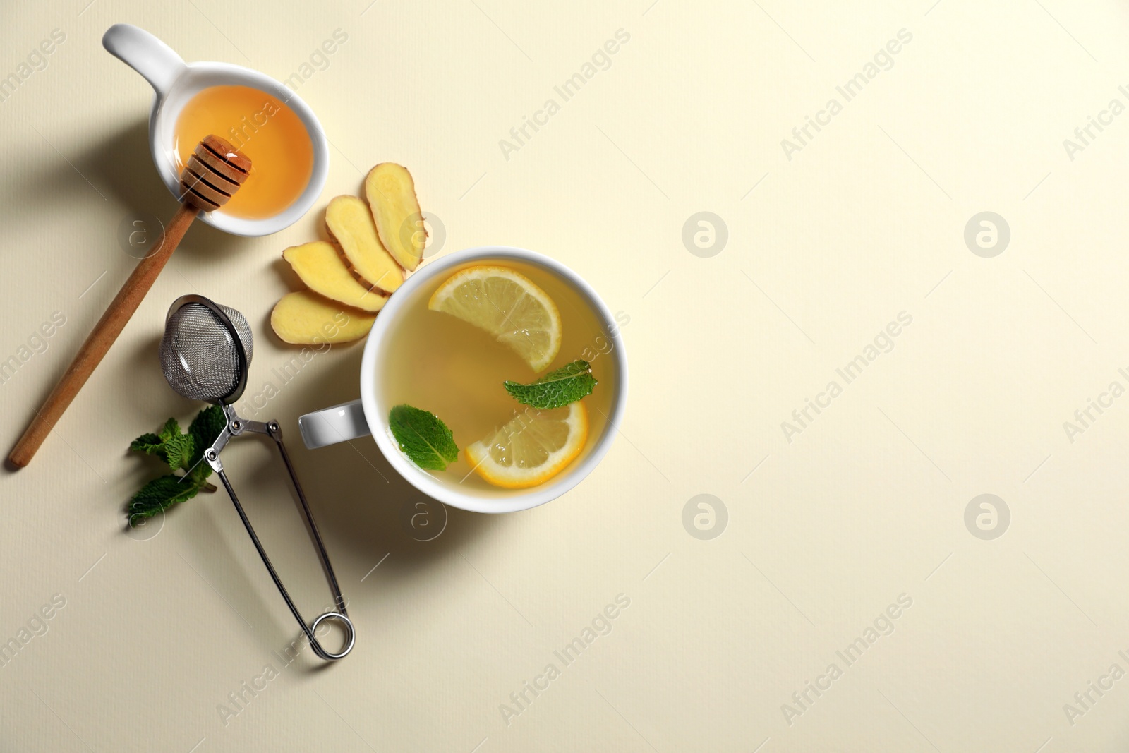 Photo of Delicious ginger tea and ingredients on beige background, flat lay. Space for text