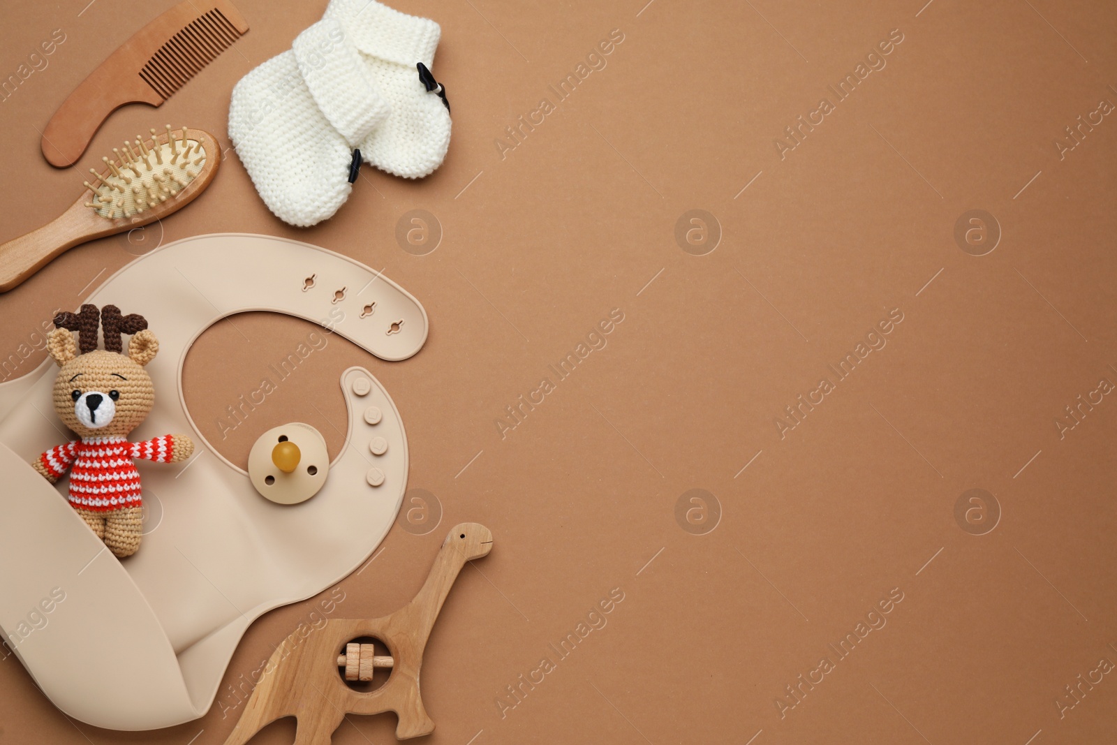 Photo of Flat lay composition with baby accessories and bib on brown background, space for text