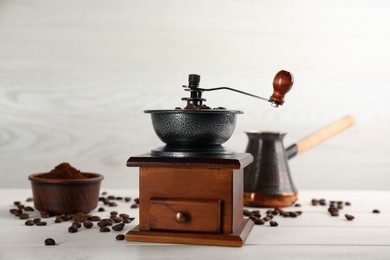 Vintage manual coffee grinder, powder and beans on white wooden table