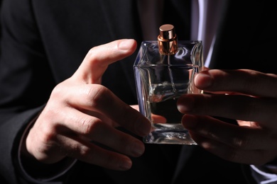 Photo of Man holding bottle of luxury perfume, closeup view