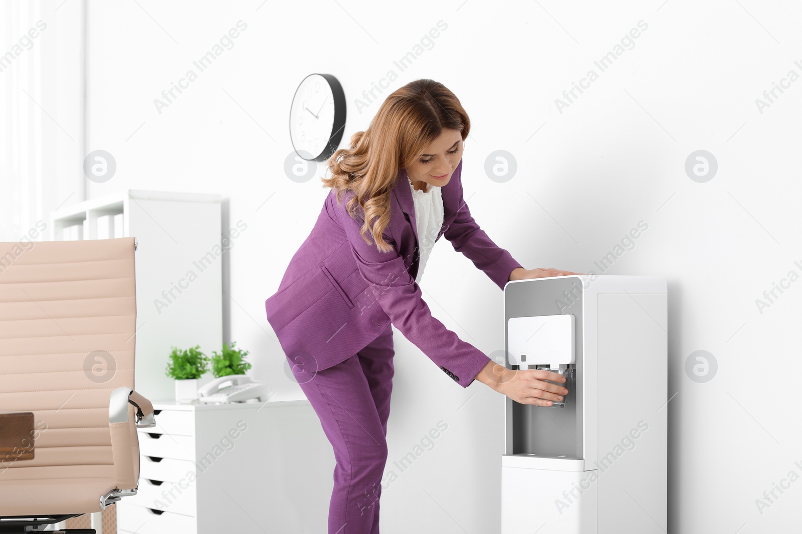 Photo of Woman having break near water cooler at workplace