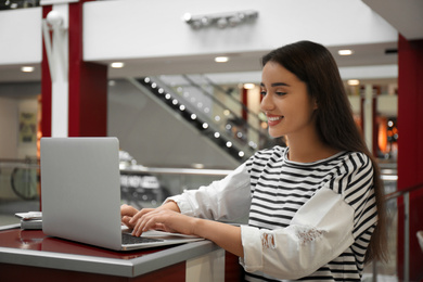 Young blogger working with laptop in mall