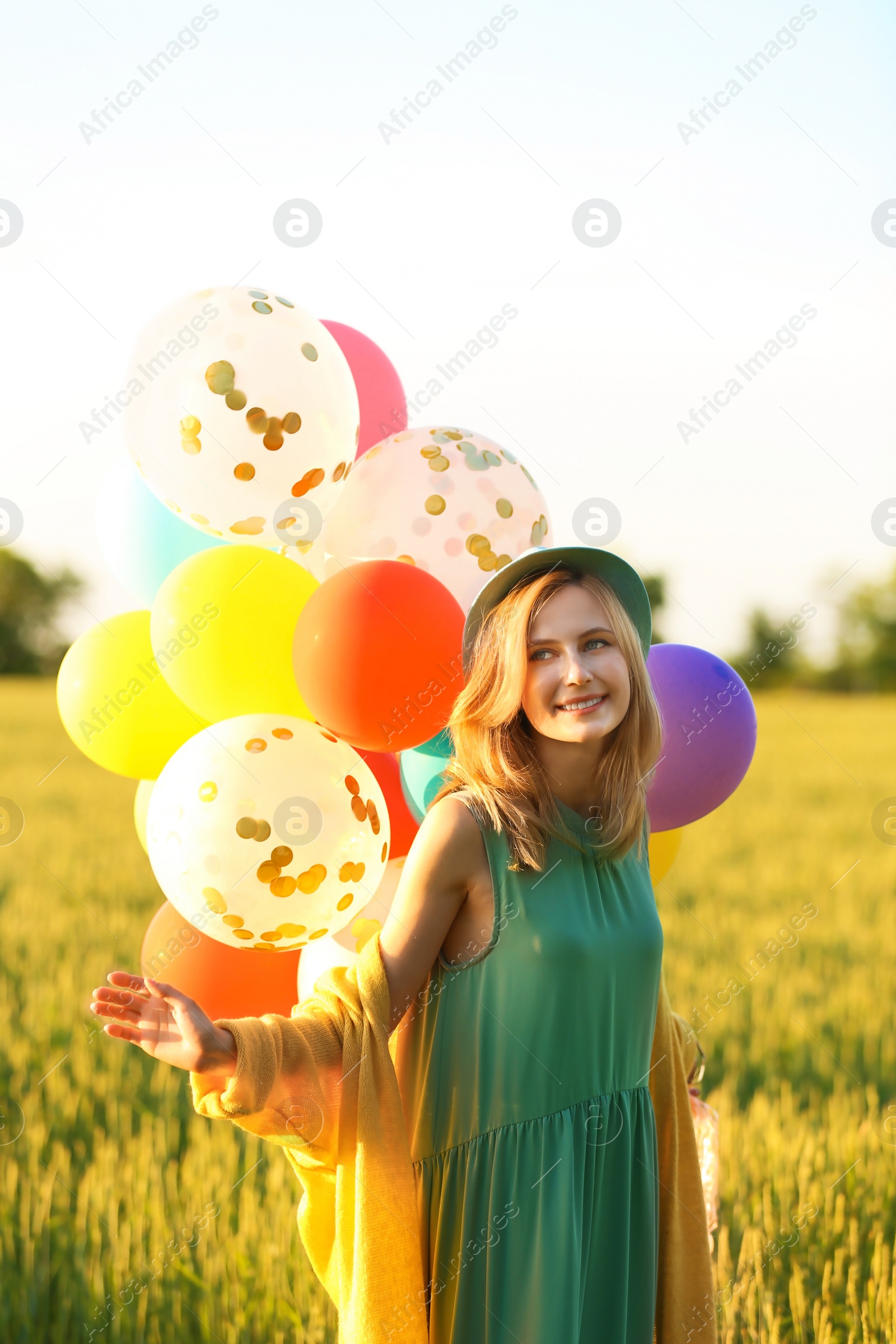 Photo of Young woman with colorful balloons in field on sunny day