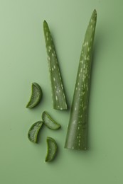 Photo of Cut aloe vera leaves on green background, flat lay