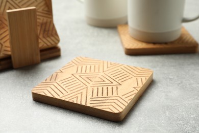 Stylish wooden cup coasters on light grey table