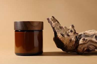 Photo of Jar of luxury cream and tree bark on dark beige background