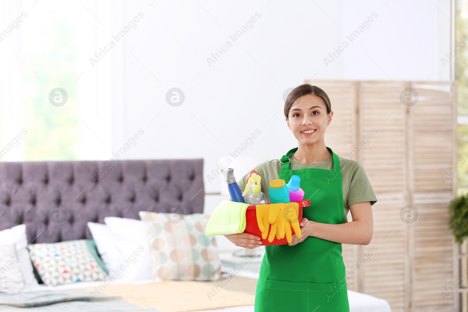 Photo of Woman in uniform with cleaning supplies indoors