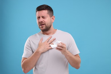 Photo of Man suffering from allergy on light blue background
