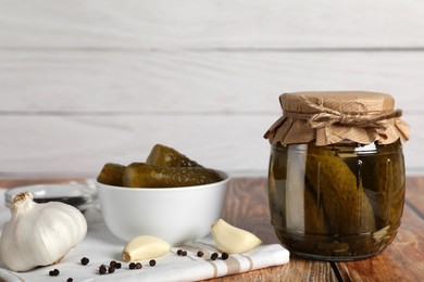 Photo of Jar with tasty pickled cucumbers and ingredients on wooden table