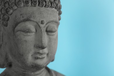 Photo of Beautiful stone Buddha sculpture on light blue background, closeup. Space for text