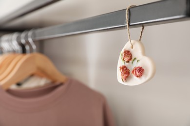Photo of Beautiful scented sachet and clothes hanging in wardrobe