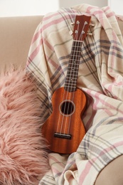 Photo of Brown wooden guitar on sofa at home