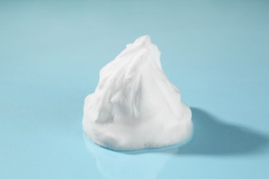 Sample of cleansing foam on light blue background, closeup. Cosmetic product
