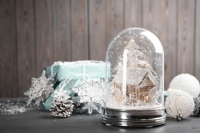 Photo of Beautiful snow globe, Christmas decor and gifts on grey wooden table. Space for text