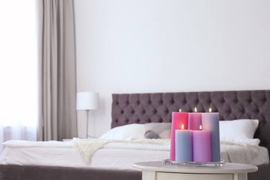 Burning candles on table in light bedroom