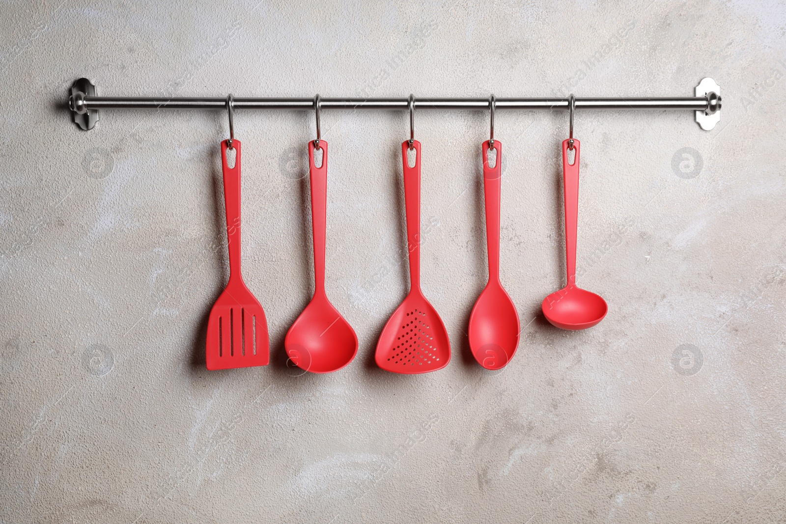 Photo of Rack with clean kitchen utensils on color wall